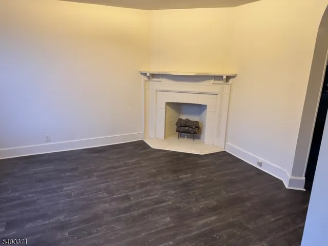 a view of an empty room with wooden floor and a fireplace