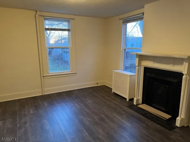 an empty room with wooden floor a fireplace and windows