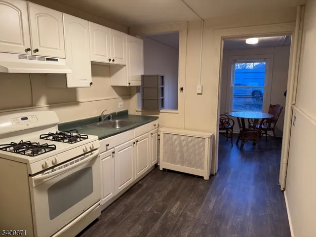 a white kitchen with wooden floors and white stainless steel appliances