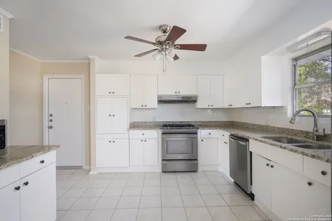 a kitchen with white cabinets granite counter tops and a stove