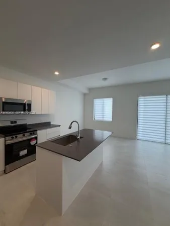 a kitchen with stainless steel appliances a stove and white cabinets