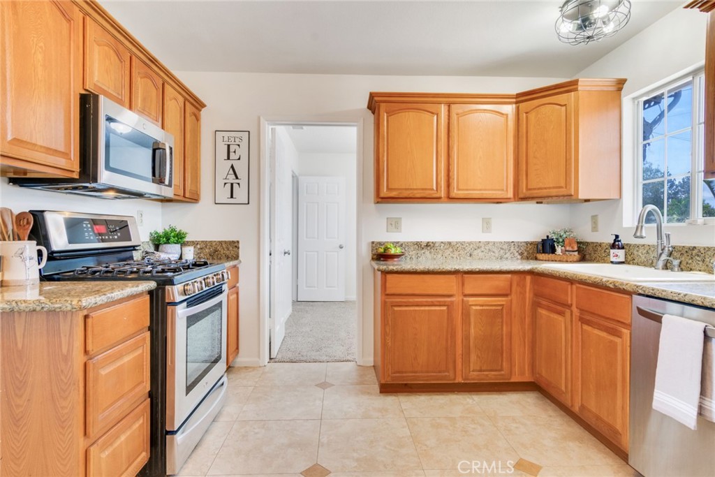 8955 Holly Lane Riverside, CA 92503 - Photo 5 of 32 a kitchen with stainless steel appliances granite countertop a stove top oven a sink dishwasher and a refrigerator with wooden cabinets