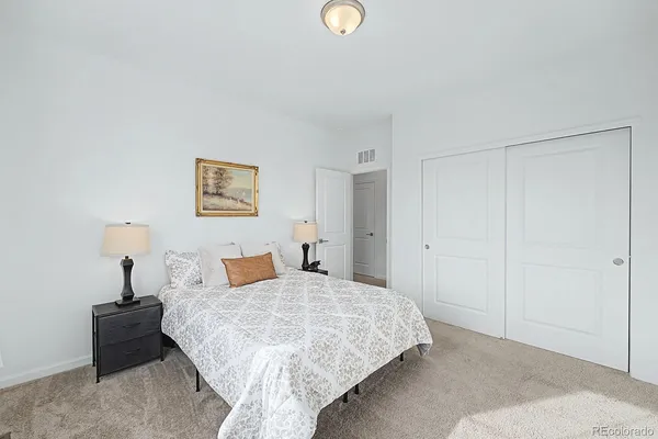 a bedroom with a bed and a lamp on the dresser