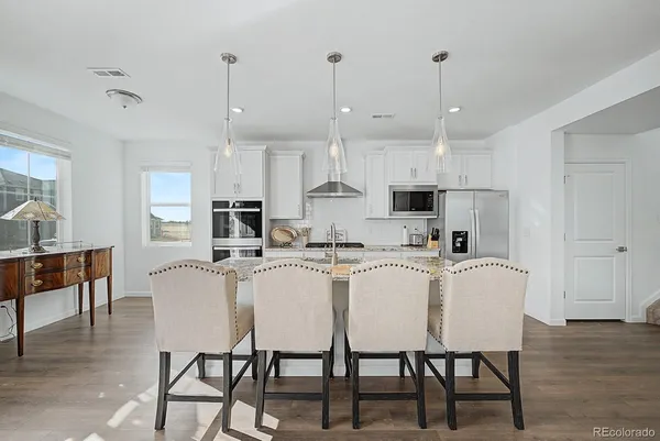 a kitchen with stainless steel appliances a white table chairs and a refrigerator