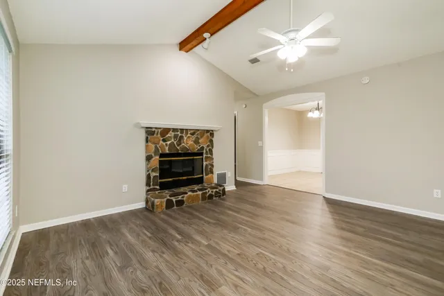 an empty room with wooden floor and a ceiling fan