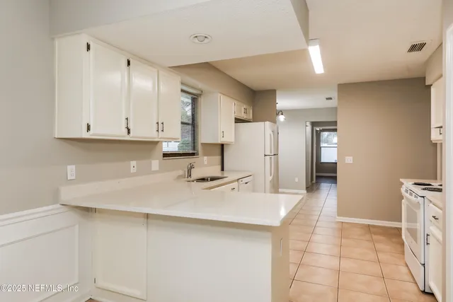 a kitchen with kitchen island a sink a stove a refrigerator and white cabinets