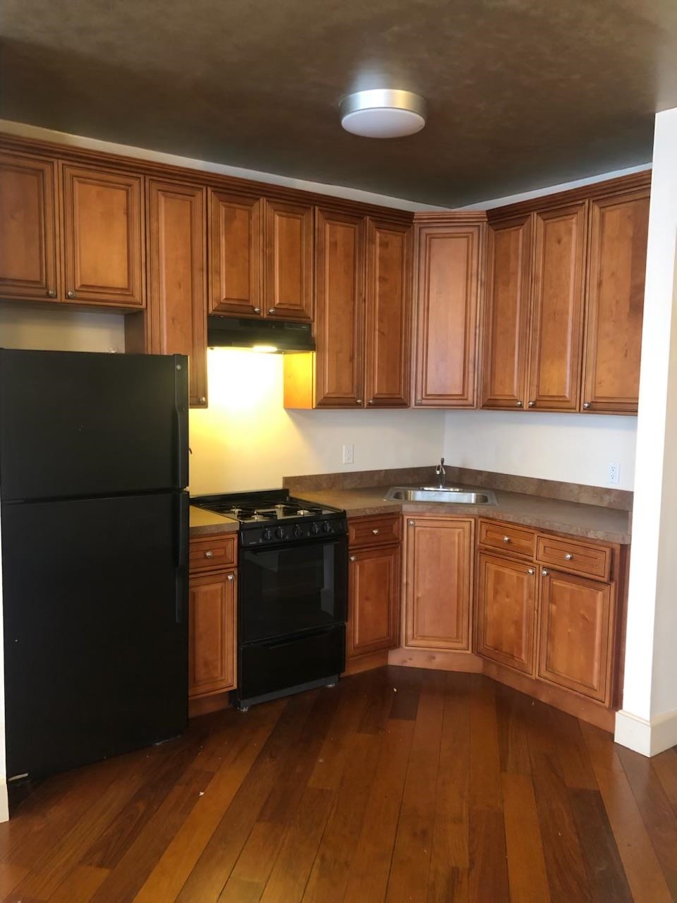 a kitchen with granite countertop wooden cabinets and a refrigerator