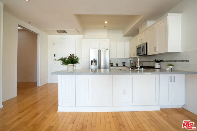 a kitchen with stainless steel appliances granite countertop a refrigerator sink and white cabinets