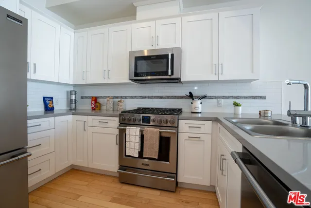 a kitchen with white cabinets stainless steel appliances and sink