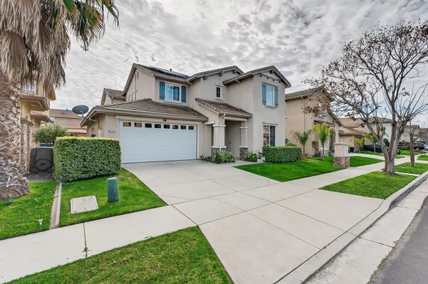a front view of a house with a garden and palm trees