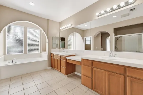 a spacious bathroom with a granite countertop sink mirror and bathtub