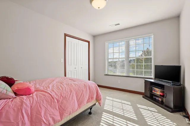 a bedroom with a bed and a flat tv screen on a dresser