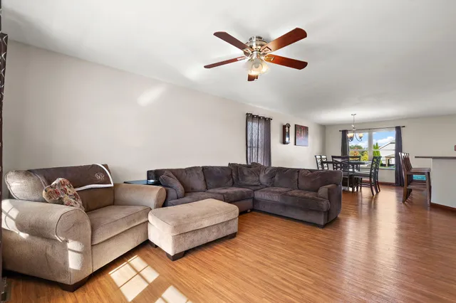 a living room with couches and kitchen view with wooden floor