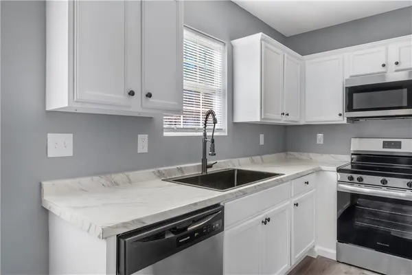 a kitchen with granite countertop white cabinets and a stove