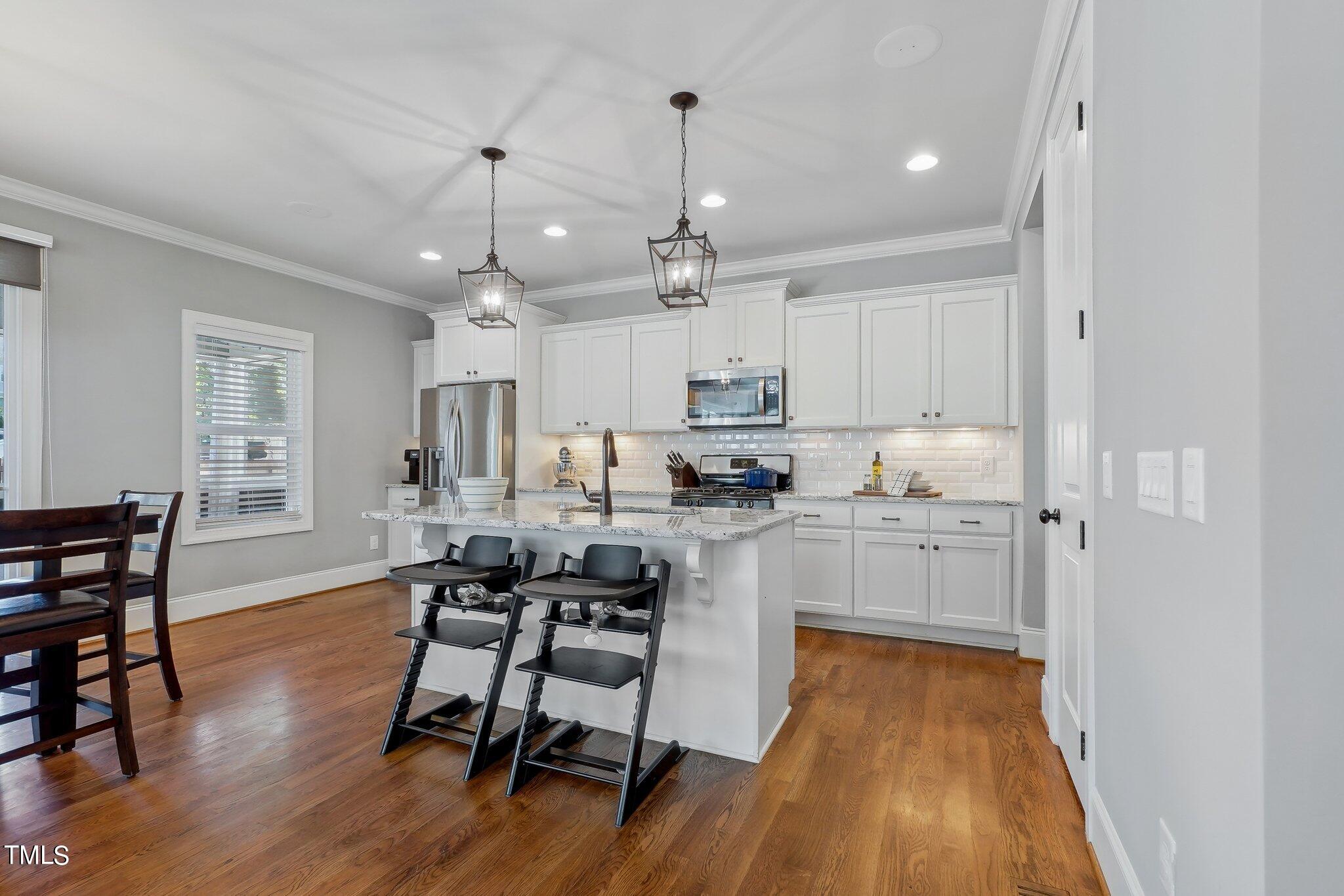 103 Pineland Circle Raleigh, NC 27606 - Photo 11 of 62 a kitchen with stainless steel appliances granite countertop a white cabinets and wooden floor