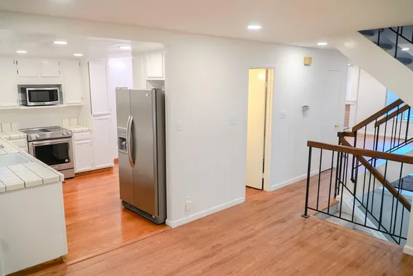 an empty room with wooden floor and stainless steel appliances