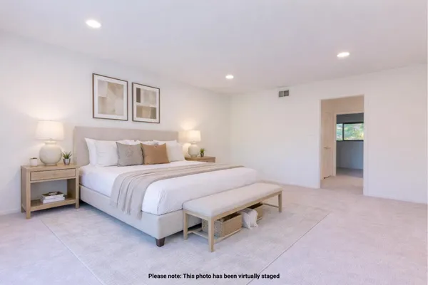 a spacious bedroom with a bed and a lamp