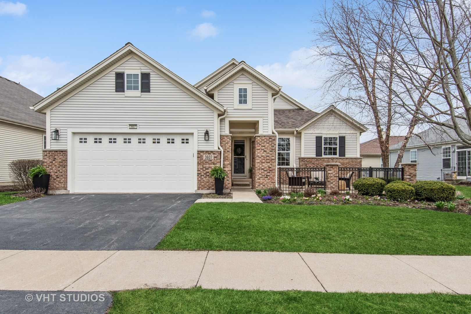 a view of a yard in front of a house with plants and large tree