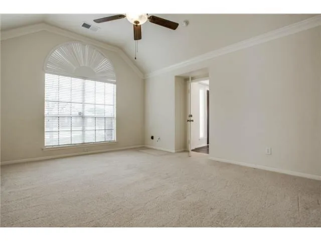 an empty room with windows and ceiling fan