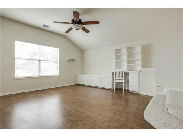 a view of an empty room with a window and wooden floor