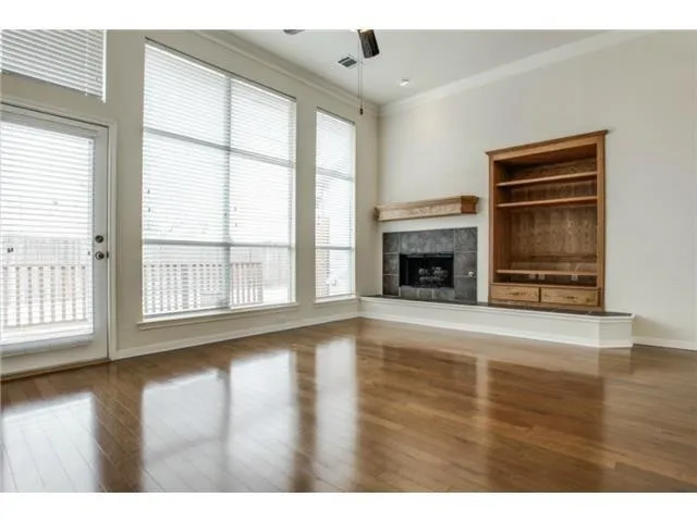 a view of an empty room with wooden floor fireplace and a window