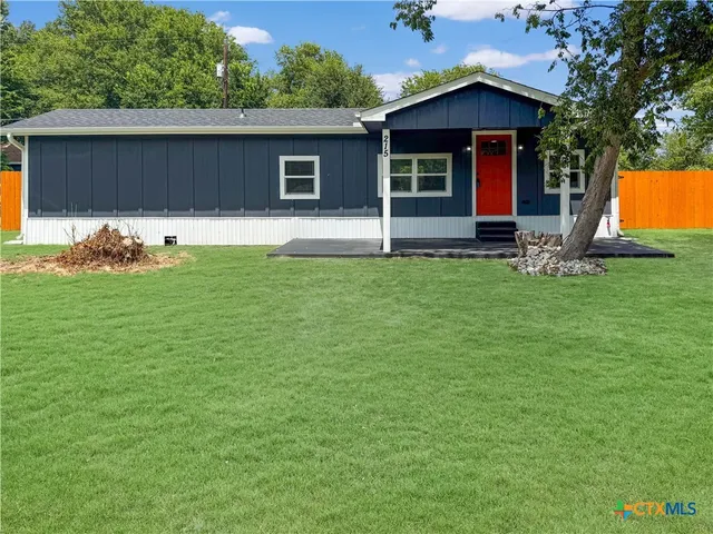 a front view of house with yard and trees in the background