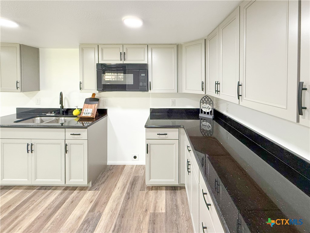 215 East Valley Road Harker Heights, TX 76548 - Photo 5 of 16 a kitchen with granite countertop white cabinets and black appliances