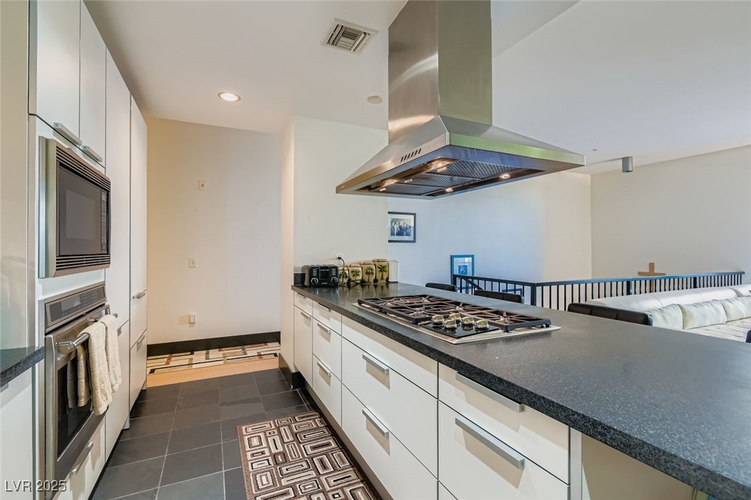 2755 West Pebble Road, Unit 319 Las Vegas, NV 89123 - Photo 20 of 29 Kitchen with white cabinets, island range hood, appliances with stainless steel finishes, dark tile patterned floors, and recessed lighting