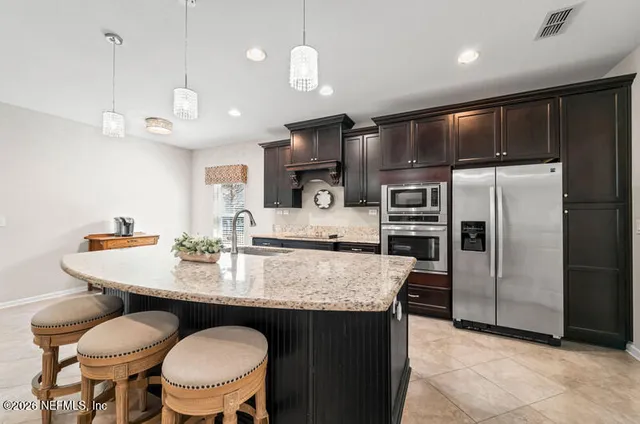 a kitchen with granite countertop a table chairs microwave and refrigerator