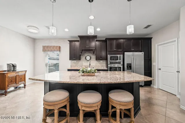 a kitchen with a dining table chairs cabinets and stainless steel appliances