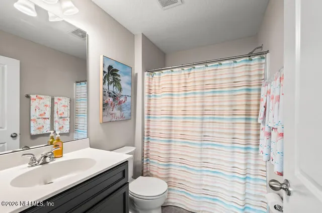 a bathroom with a sink a toilet a mirror and shower curtain