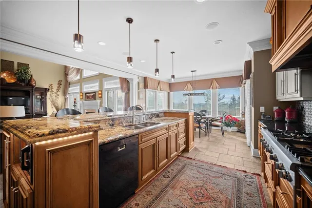 a kitchen with stainless steel appliances granite countertop a stove top oven a sink dishwasher a dining table and chairs with wooden floor