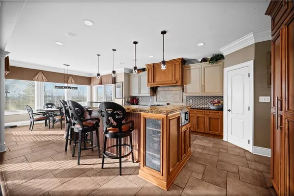 a kitchen with granite countertop a table chairs sink and refrigerator