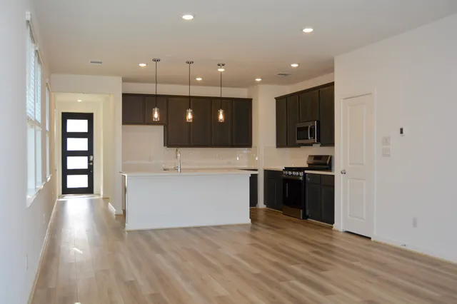 a view of a kitchen with a sink and dishwasher a oven with wooden floor