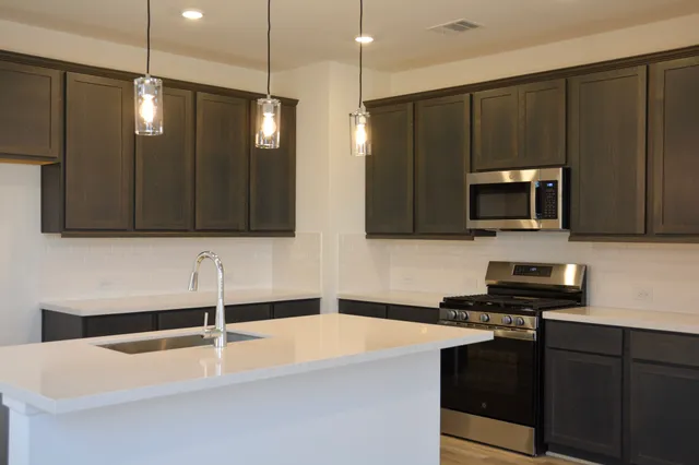 a kitchen with stainless steel appliances a stove a sink and a microwave