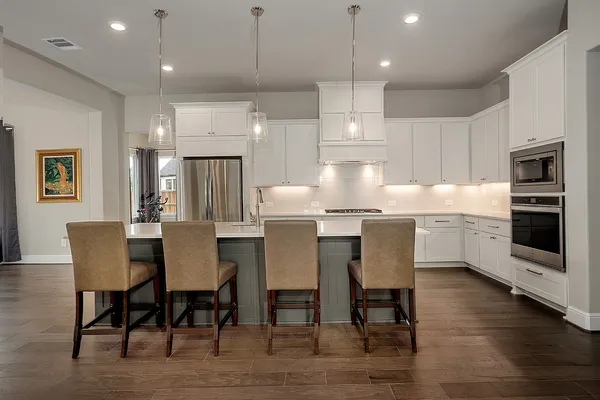 a kitchen with kitchen island a dining table chairs and white cabinets