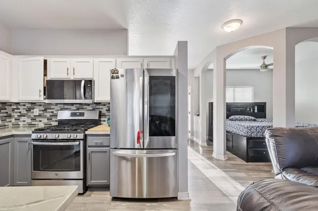 a kitchen with stainless steel appliances kitchen island granite countertop a stove top oven a sink and a refrigerator