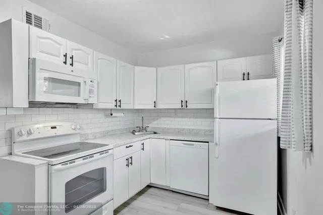 a kitchen with white cabinets sink and refrigerator