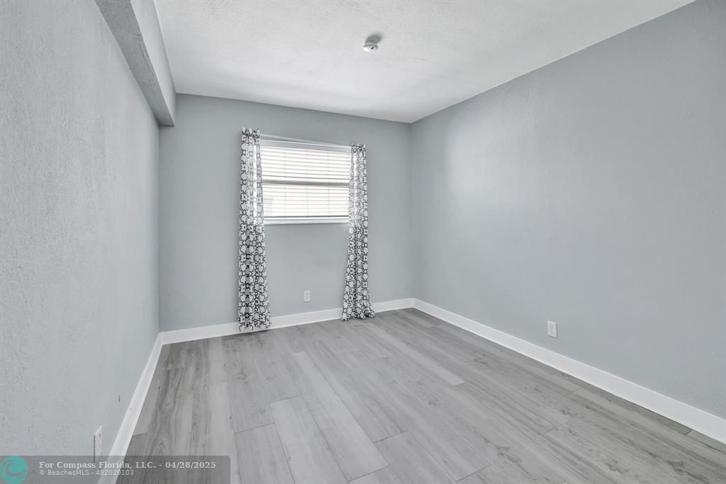 2741 Northeast 8th Avenue, Unit 15 Wilton Manors, FL 33334 - Photo 14 of 46 an empty room with wooden floor and windows