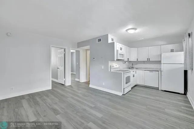 a kitchen with stainless steel appliances cabinets a wooden floor and a sink