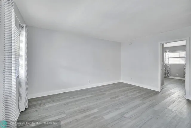 an empty room with wooden floor & windows