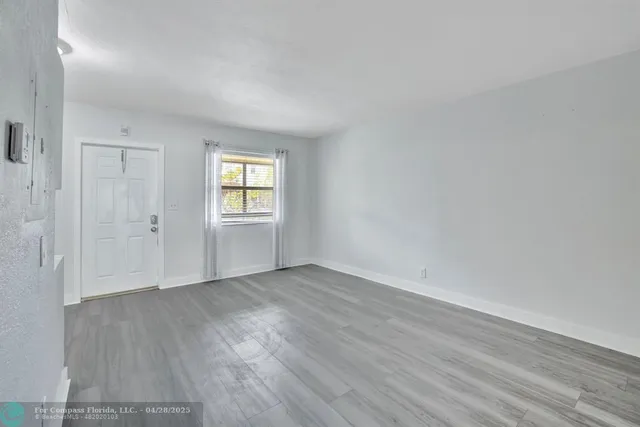 an empty room with wooden floor and window