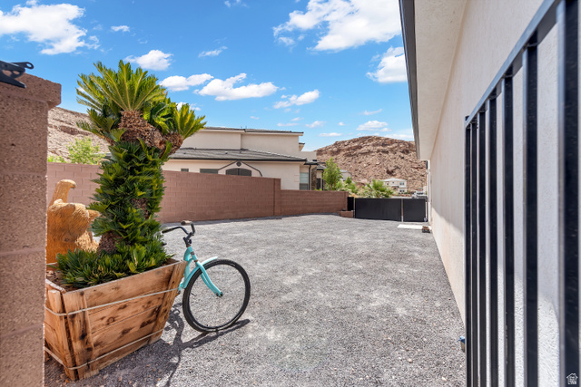 6105 Bunda Way St. George, UT 84790 - Photo 44 of 49 Gravel-covered outdoor space featuring a stucco exterior with black metal fencing, a large wood planter, and a mature palm plant