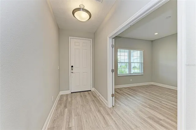 a view of an empty room with window and wooden floor