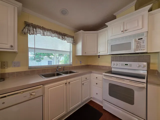 a kitchen with cabinets appliances a sink and a window