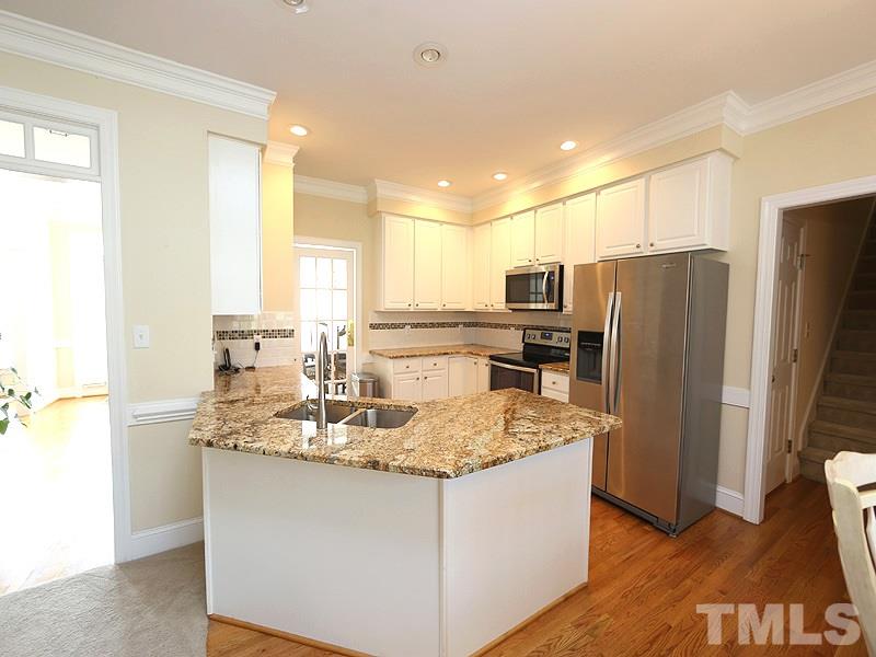 4100 Heathgate Lane Raleigh, NC 27613 - Photo 10 of 25 a kitchen with kitchen island a counter top space cabinets a sink and a refrigerator