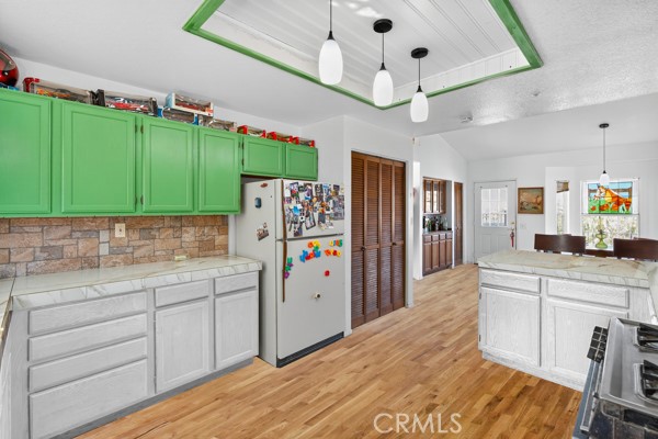 34215 Simla Street Acton, CA 93510 - Photo 13 of 37 a kitchen with stainless steel appliances kitchen island granite countertop a refrigerator a stove a sink dishwasher and white cabinets with wooden floor