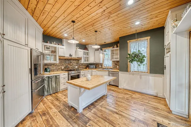 a large white kitchen with wooden floors and stainless steel appliances