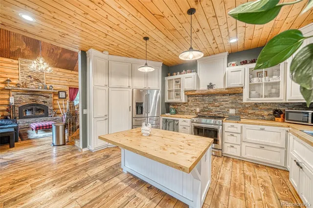 a kitchen with stainless steel appliances kitchen island granite countertop a refrigerator a stove and a wooden floors