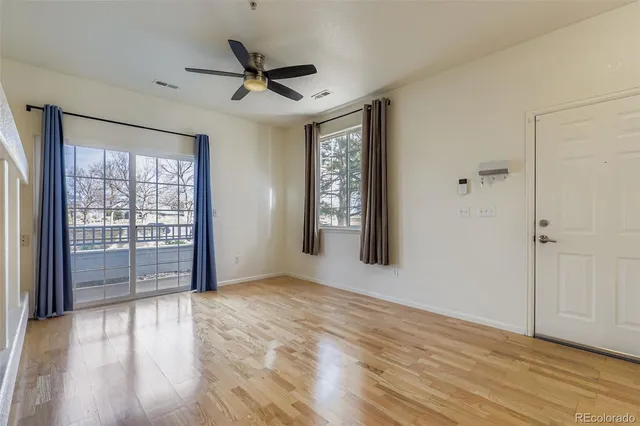 a view of an empty room with a window and wooden floor